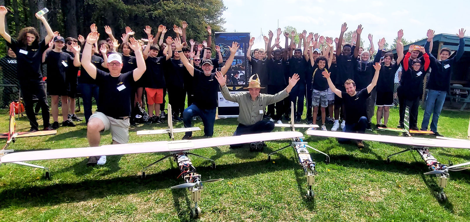 accueil_image6-3_aviation-connection Groupe d'étudiants et professeurs avec trois avions-cargo télécommandés fabriqués dans le cadre du programme STIM d'Aviation Connection.